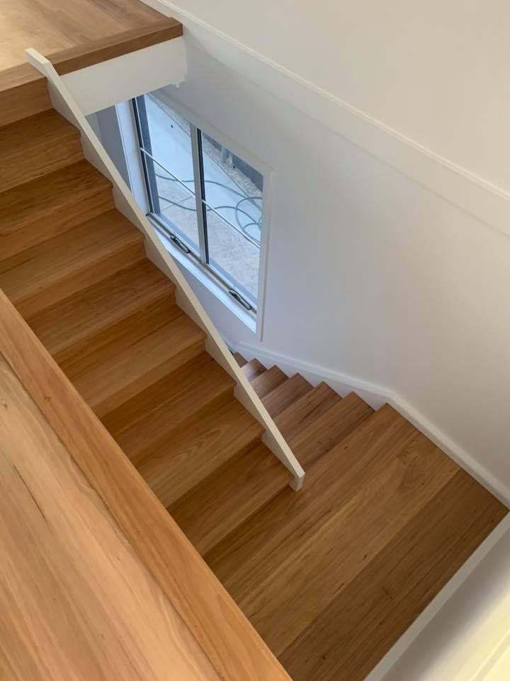Wooden staircase with white handrail and window.
