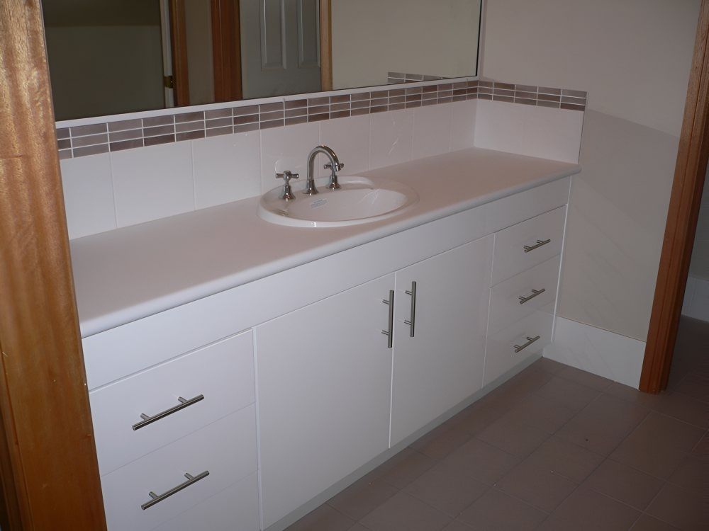 A Bathroom Vanity With A Sink, A Mirror, and A White Cabinet — Gavin Cummings Kitchens in Condobolin, NSW