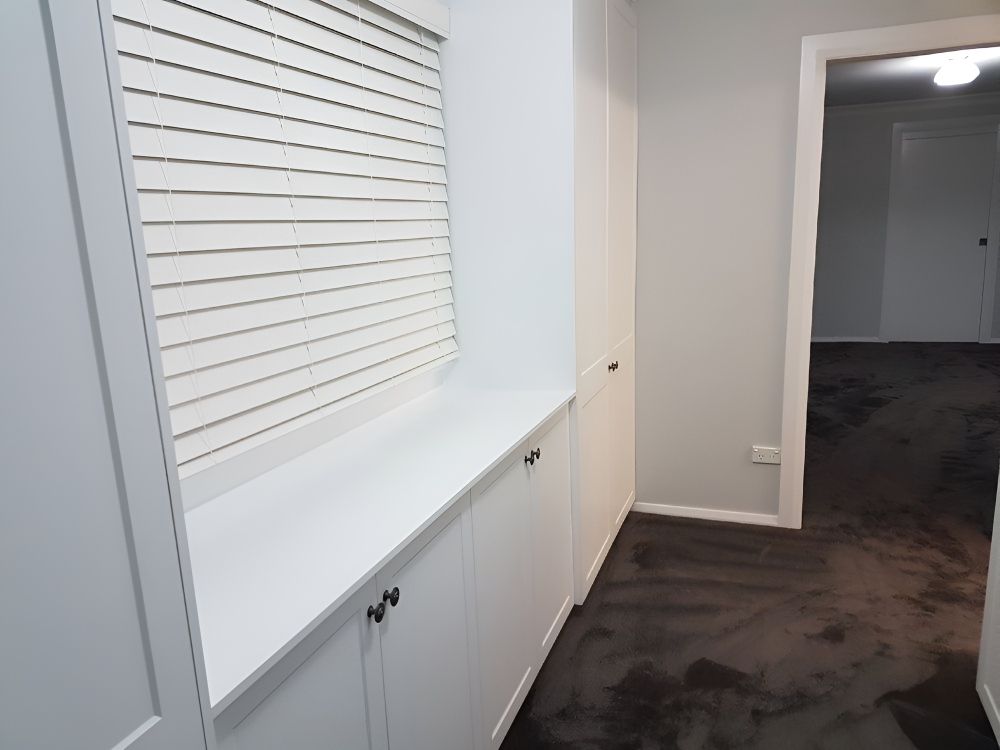 A Hallway With White Cabinets And Black Carpet — Gavin Cummings Kitchens in Dubbo, NSW