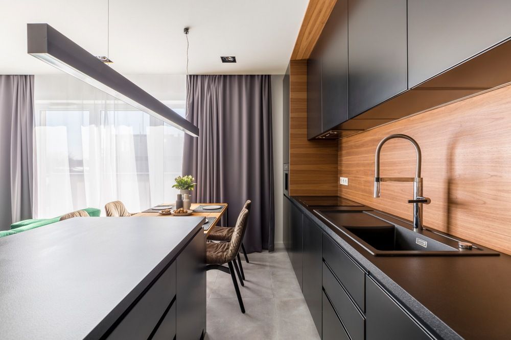 A Kitchen With Black Cabinets , a Sink , and a Dining Room in the Background — Gavin Cummings Kitchens in Dubbo, NSW