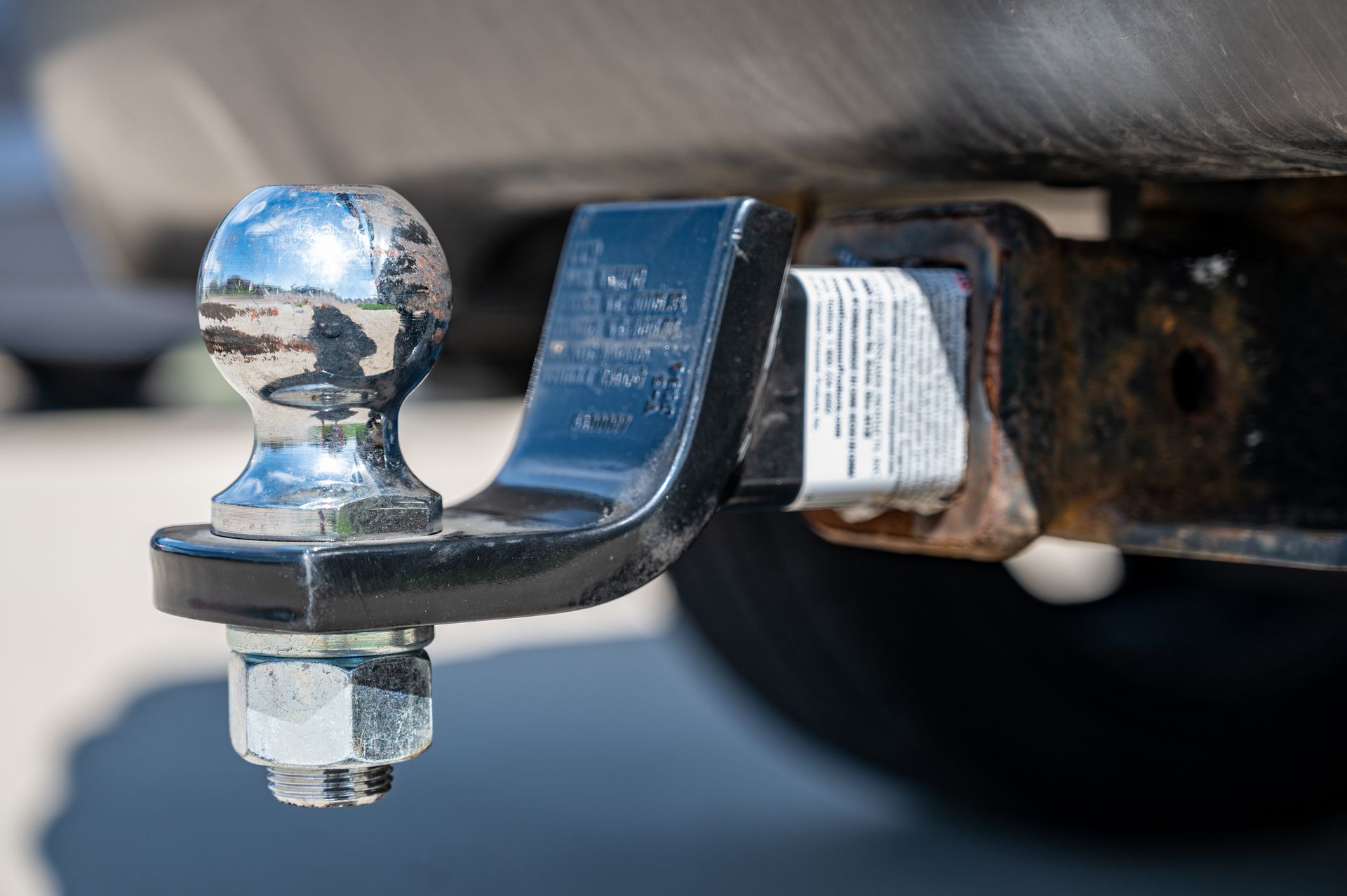 Close-up of a shiny chrome trailer hitch ball and black tow mount under a vehicle
