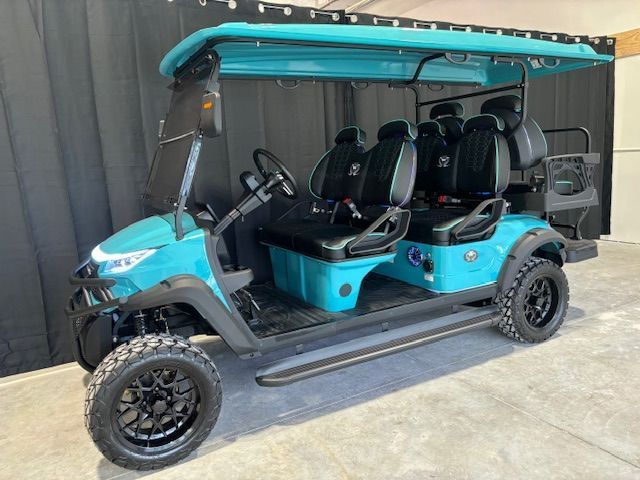 Turquoise six-seat golf cart with black roof parked on concrete near a gray wall