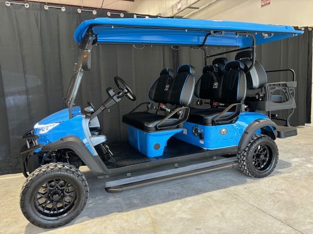 Blue four-seat golf cart with black roof and off-road tires parked indoors.