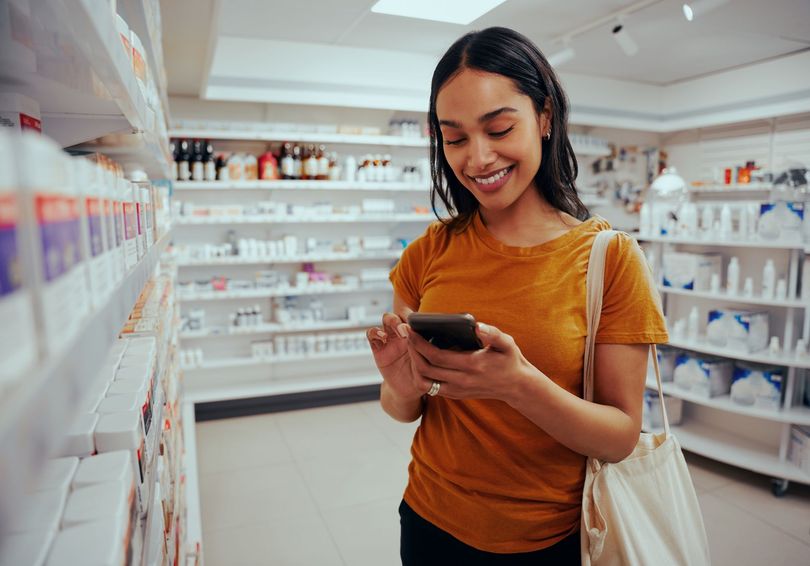 A woman is looking at her phone in a pharmacy