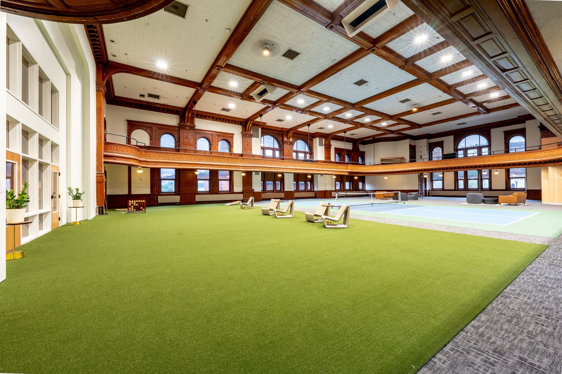 Large room with green turf, wood beams, and a second-story balcony.