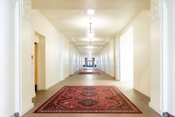 Long hallway with red rugs, white walls, and doorways leading to rooms at Zenith Apartments in Duluth, MN.