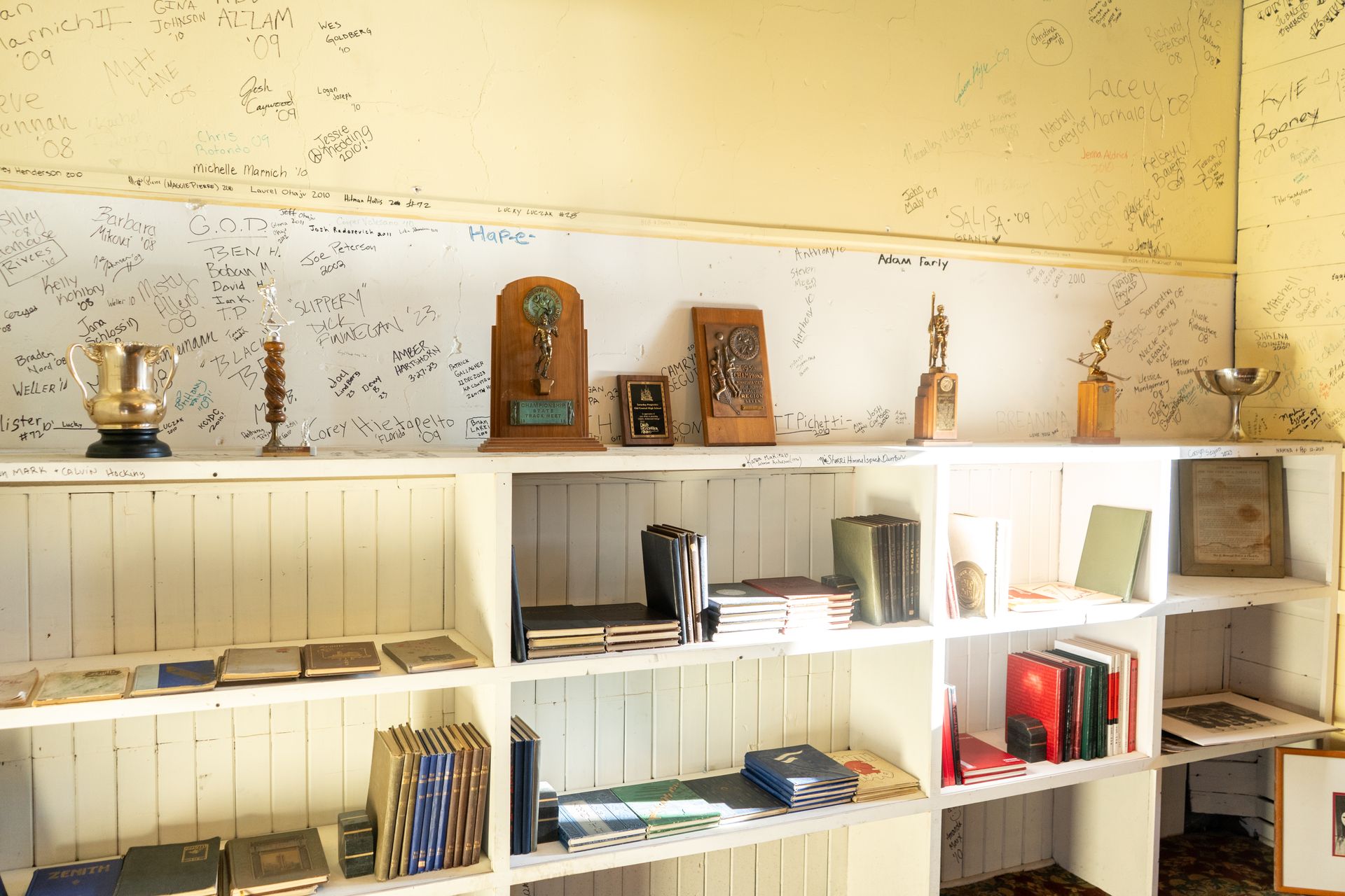 Wooden shelves with awards, books, and signed wall.