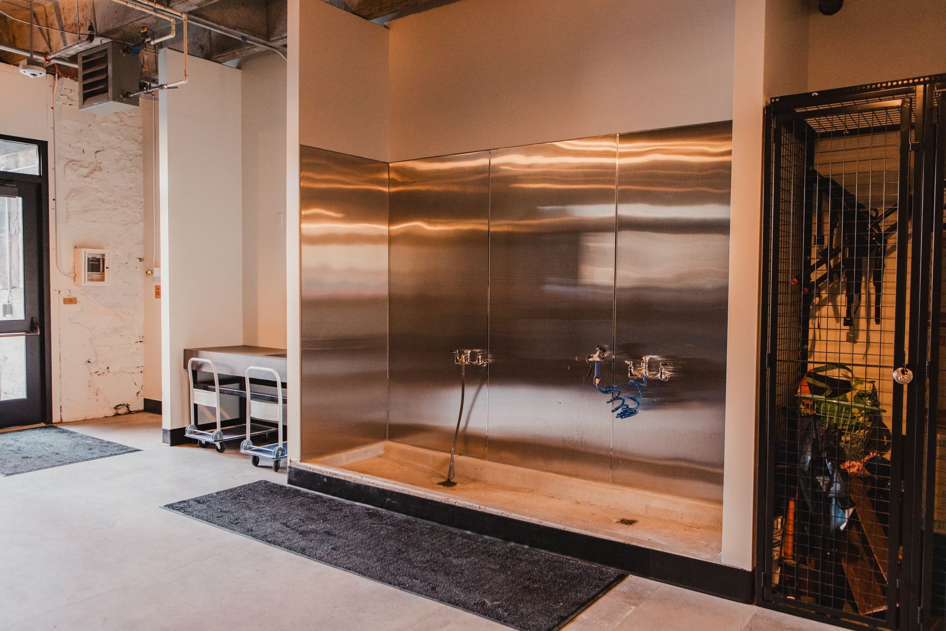 Dog wash station with stainless steel walls and a black doorway.