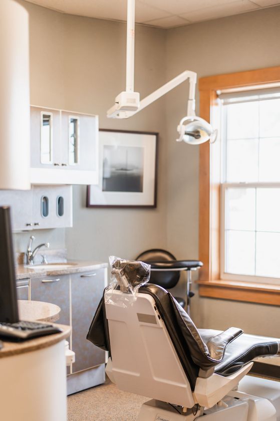 Dental exam room with chair, overhead light, sink, and window with blinds