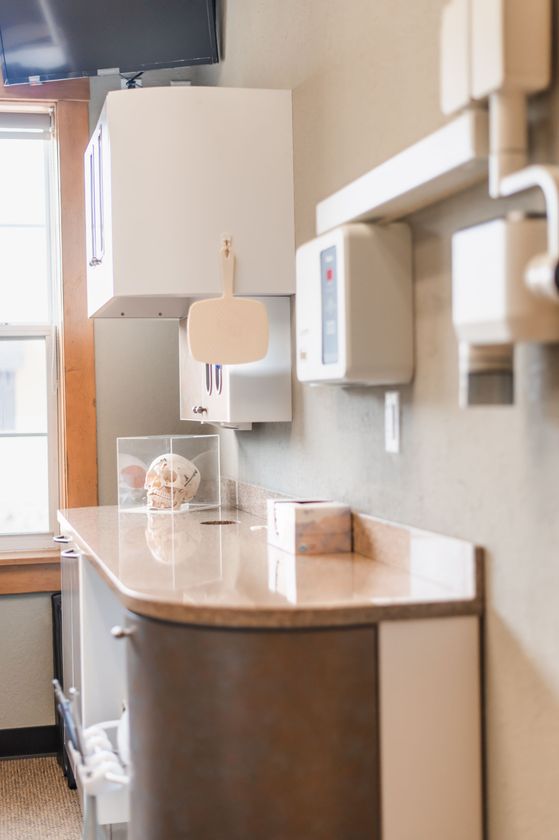 Indoor coffee station with a wall-mounted dispenser and a small cup on a wooden counter.