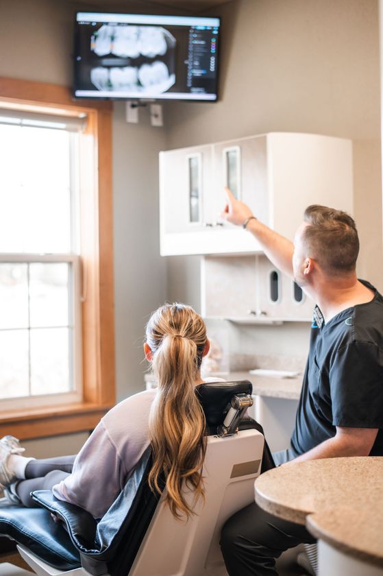 Dentist showing patient an X-ray in a bright dental exam room