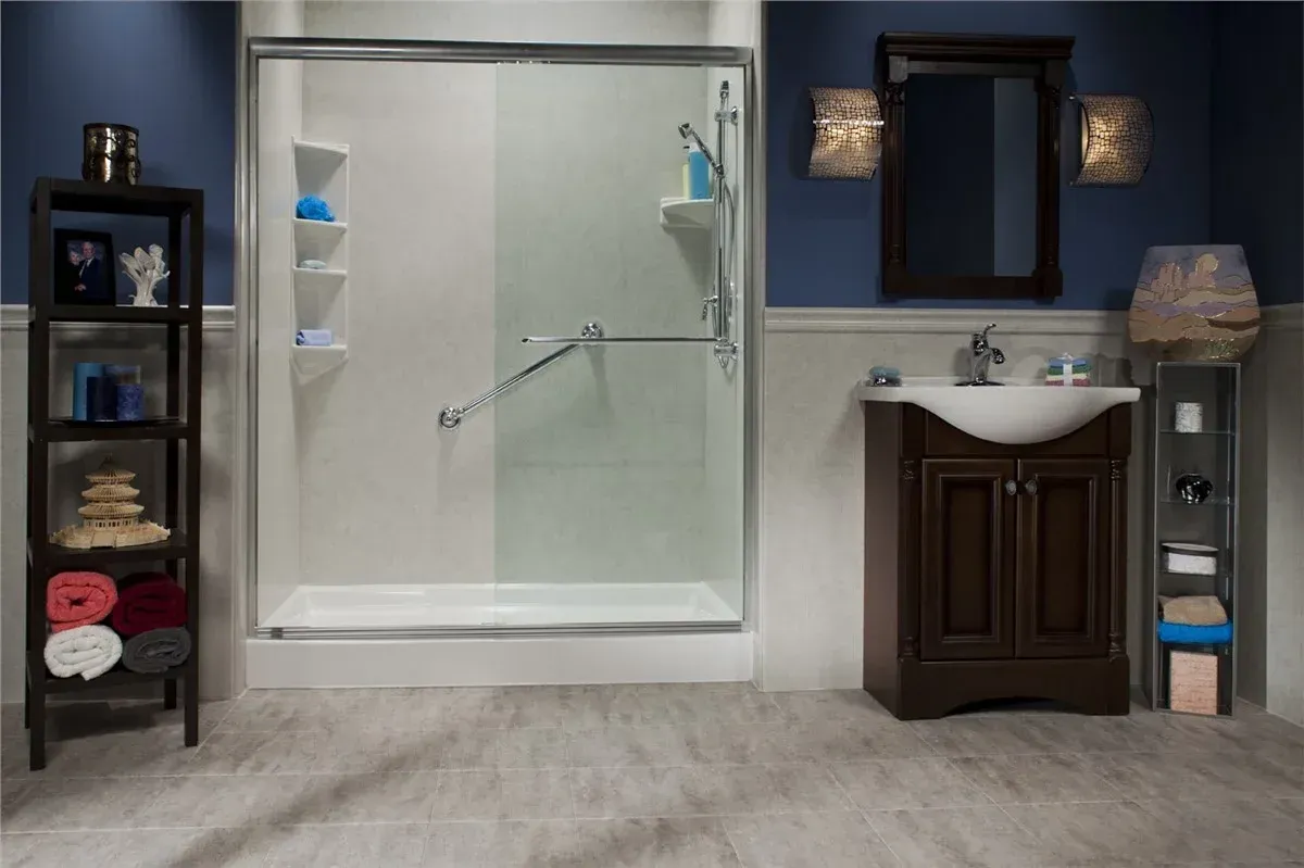 Modern bathroom with glass shower, dark vanity, mirror, shelves, and gray tile flooring.