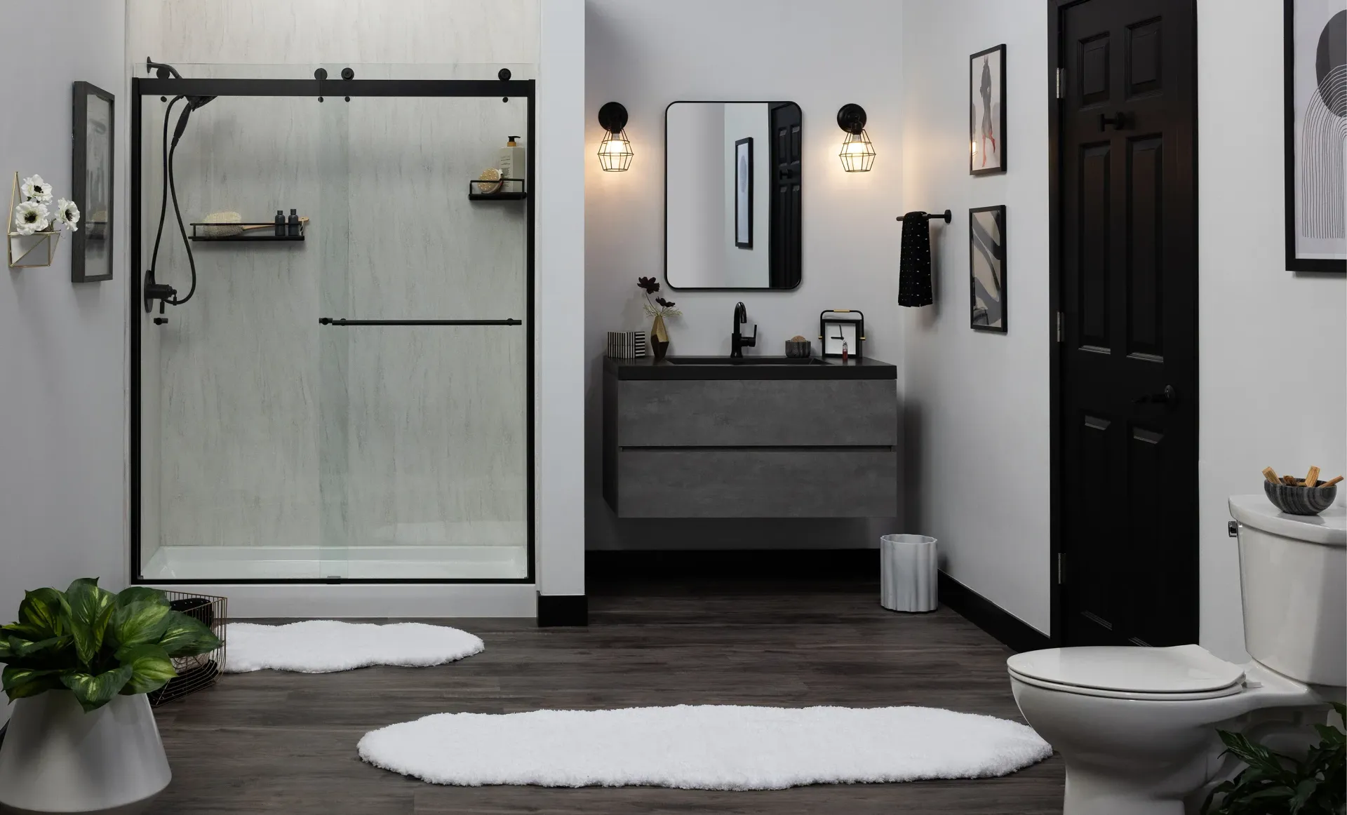 Modern black-and-white bathroom with shower, vanity, sink, toilet, and oval rugs