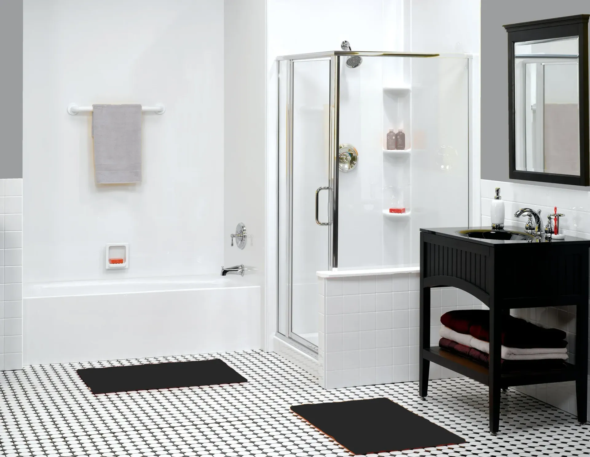 Modern bathroom with white tile, glass shower, black vanity, mirror, and two bath mats