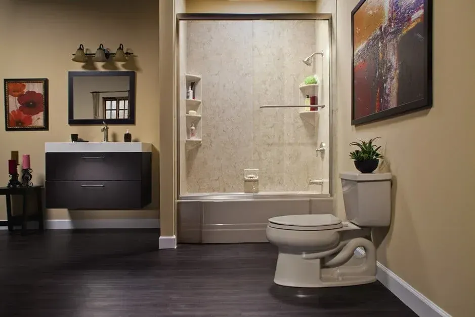 Modern bathroom with a toilet, shower, dark wood floor, and wall art.
