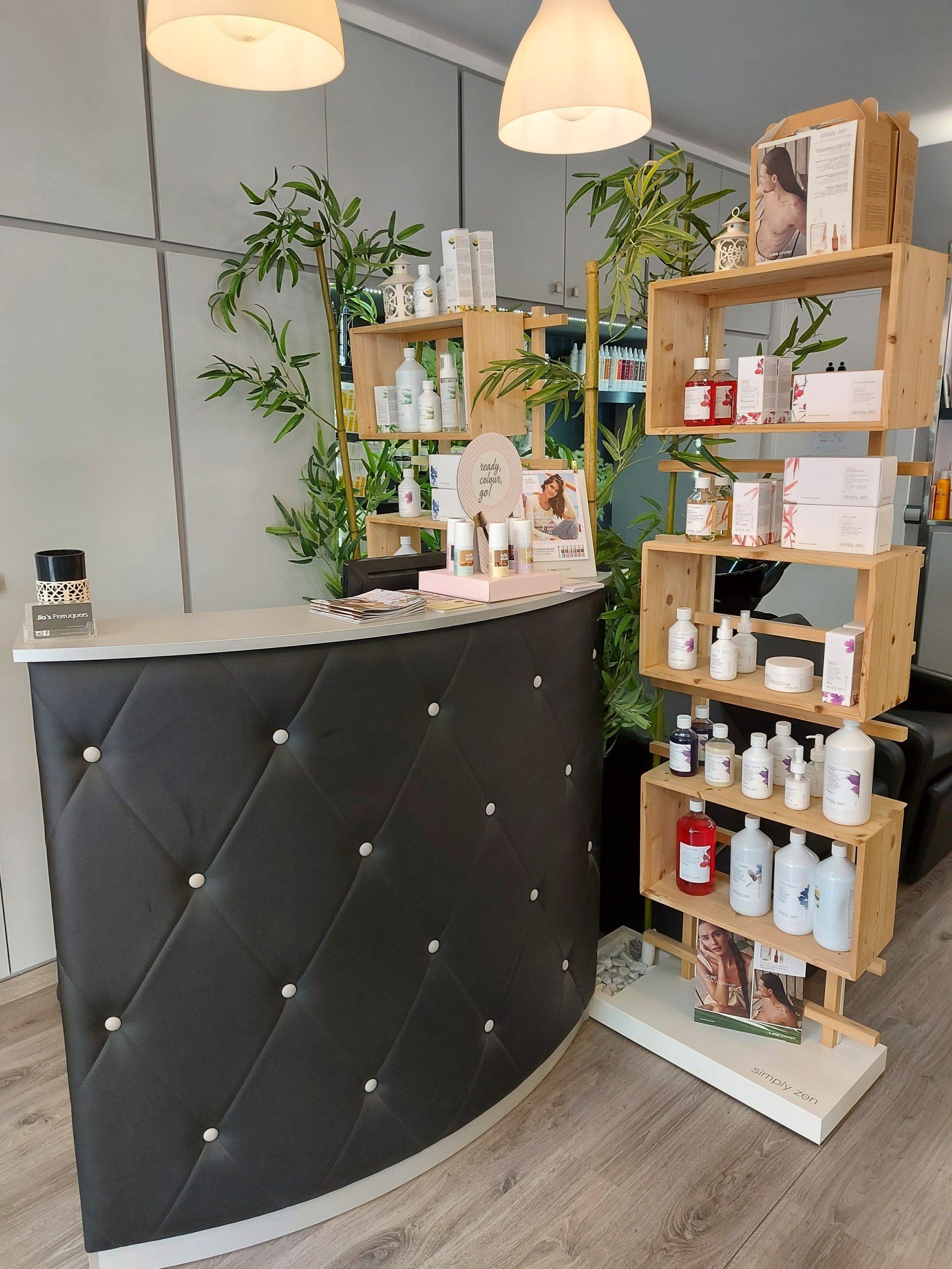Área de recepción de un salón de belleza con un escritorio acolchado negro 