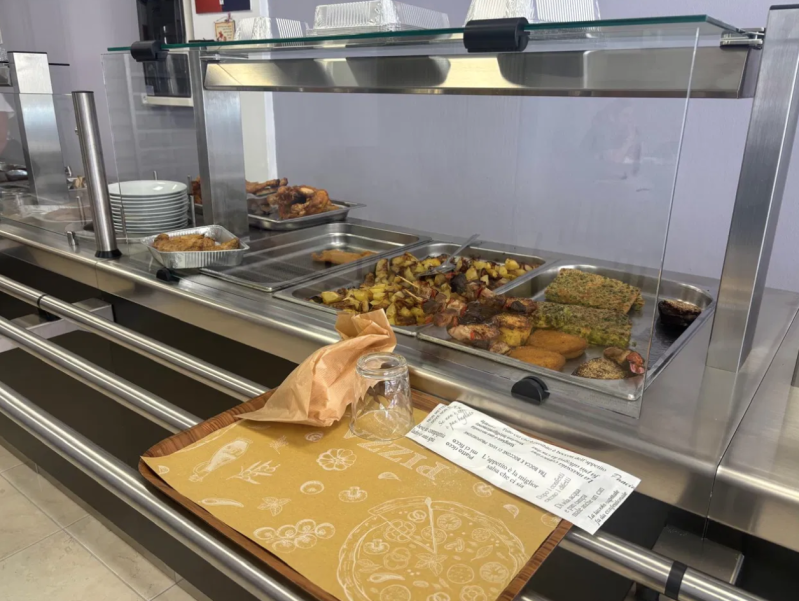 Vetrina di un bar con vassoi di pasticcini e un prodotto confezionato sul bancone