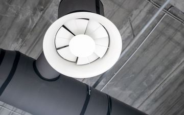Ceiling vent with white blades on a gray industrial ceiling