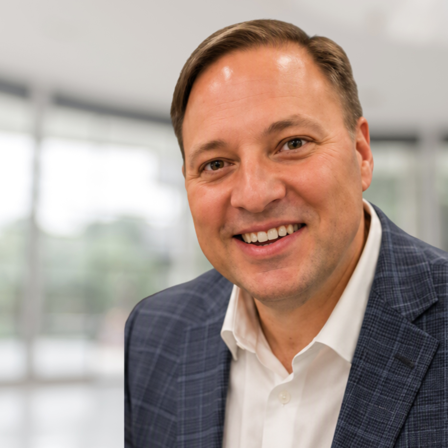Smiling man in a blue blazer and white shirt in a bright office setting