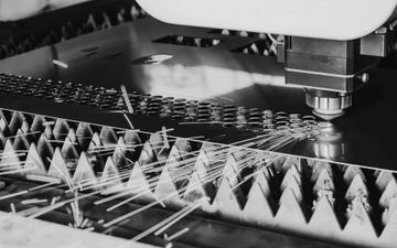 Laser cutting machine cutting triangular metal pieces on a production line