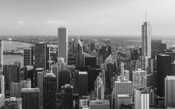 Black-and-white city skyline with dense high-rise buildings and a river in the distance