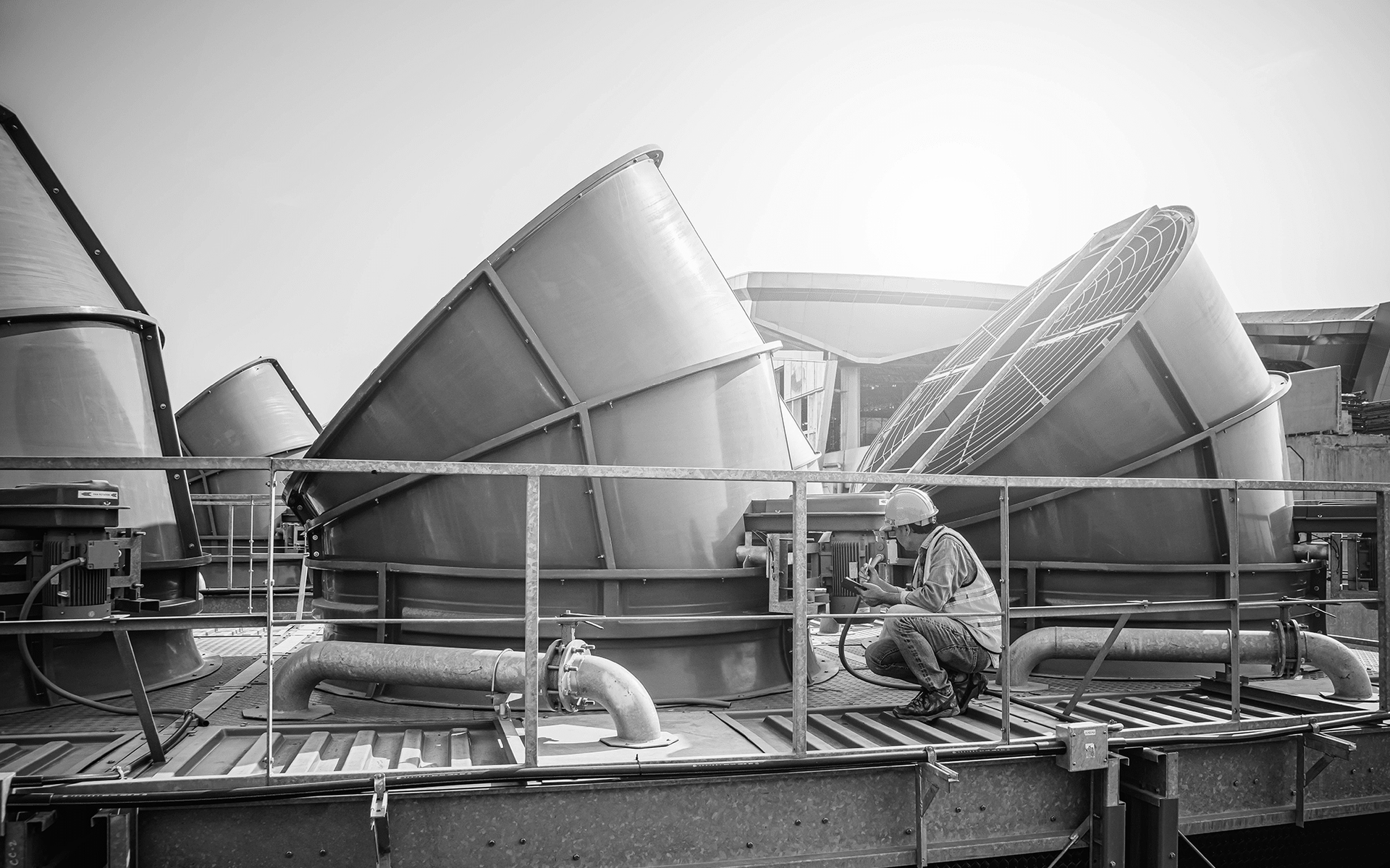 Industrial plant with large tilted vats and pipes in a black-and-white processing area