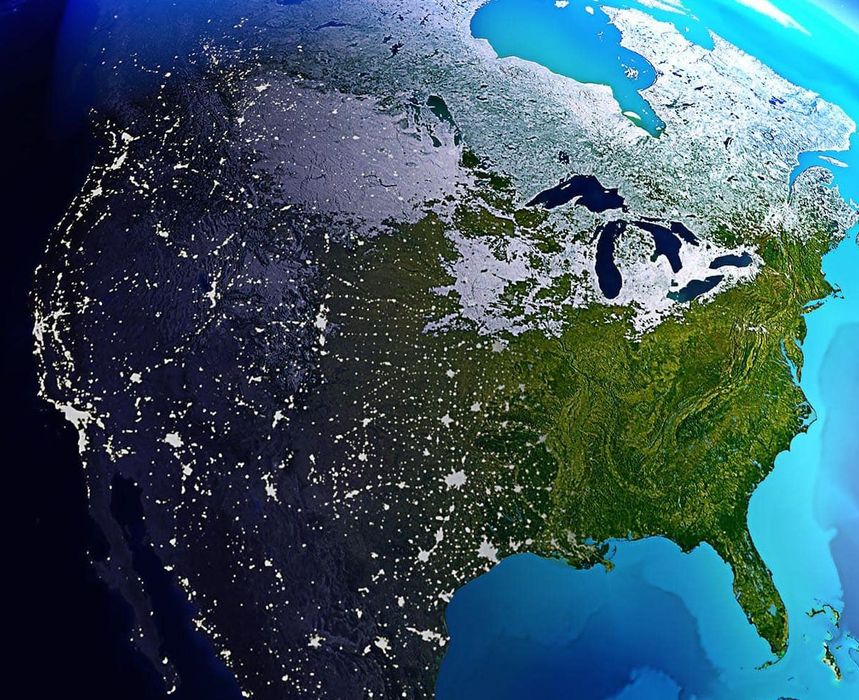 Satellite view of North America at night, with city lights and icy snow covering the north.