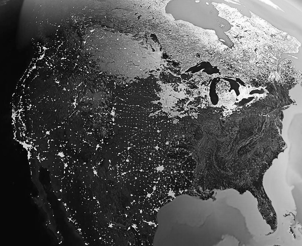 Black-and-white satellite view of North America with city lights visible at night
