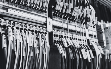 Black-and-white rows of cables and wires neatly organized on storage racks or a panel wall