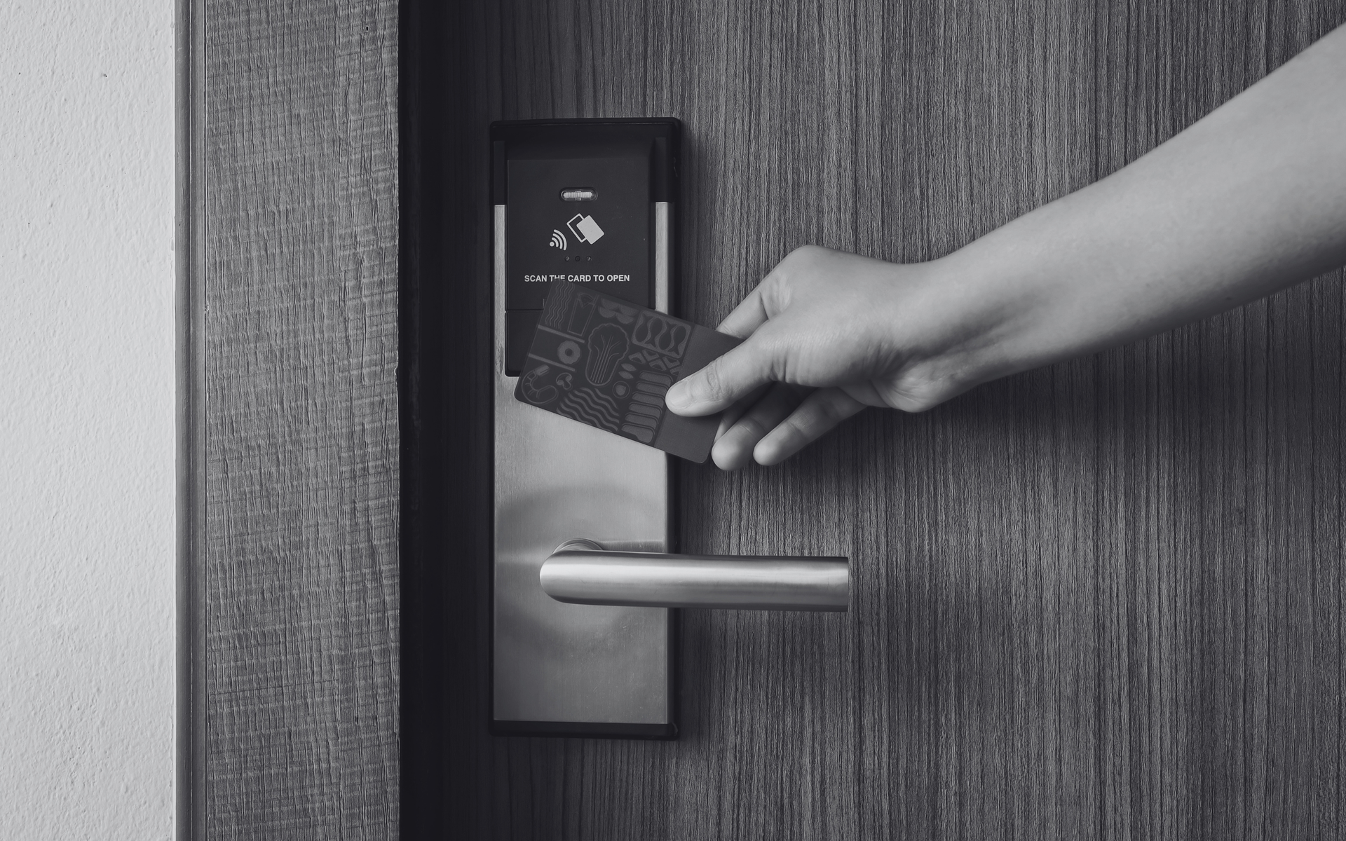 Hand holding a card to a hotel room door lock and handle