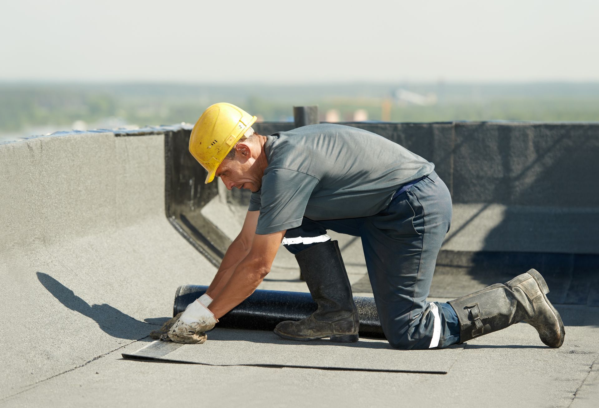 Commercial roofing contractor installing bitumen membrane on flat roof.