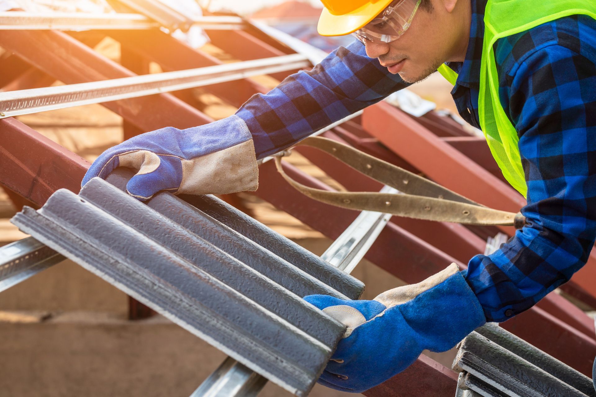 Worker installing roof tiles on metal framework during residential roofing project.