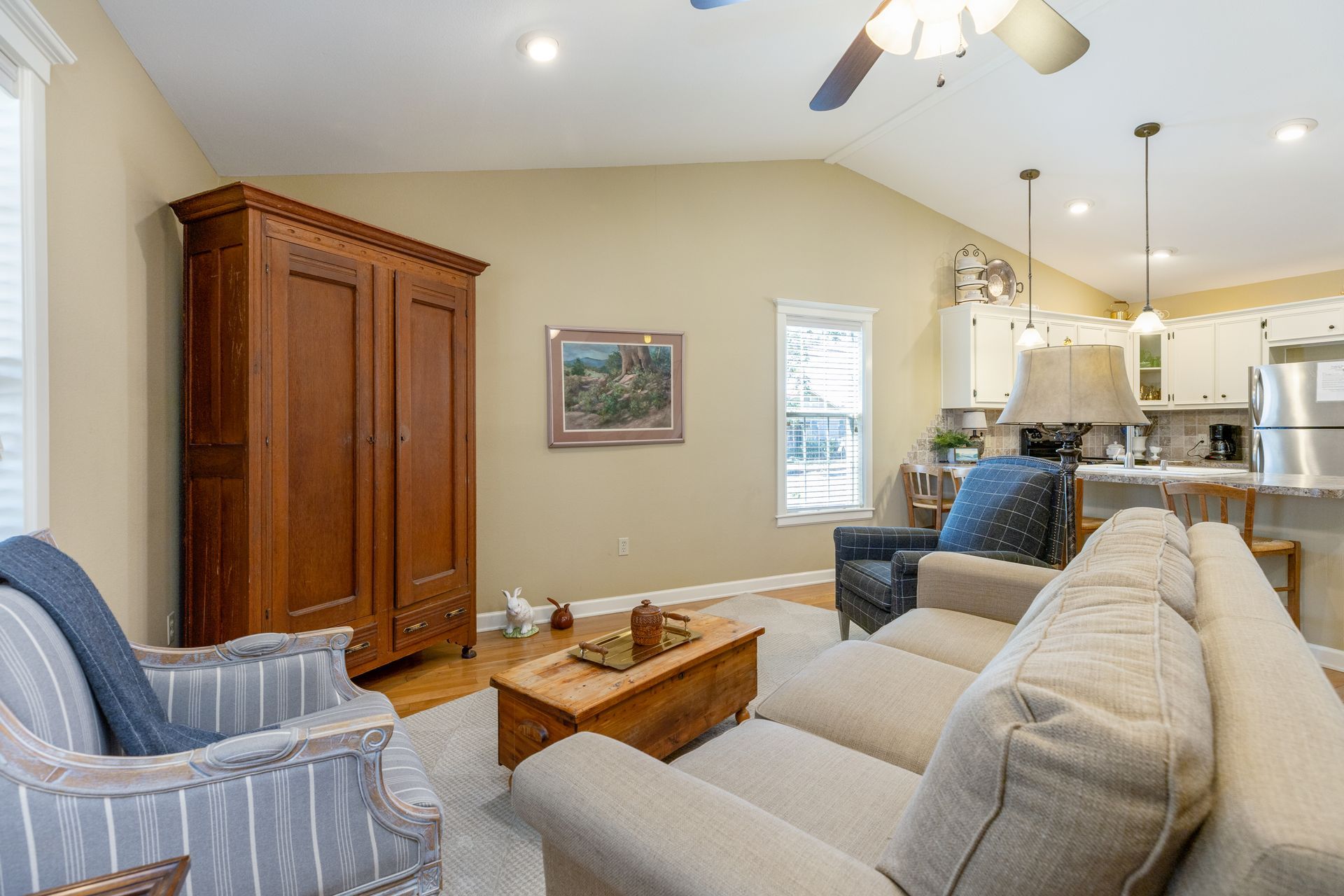 A living room with a couch , chair , coffee table and ceiling fan.