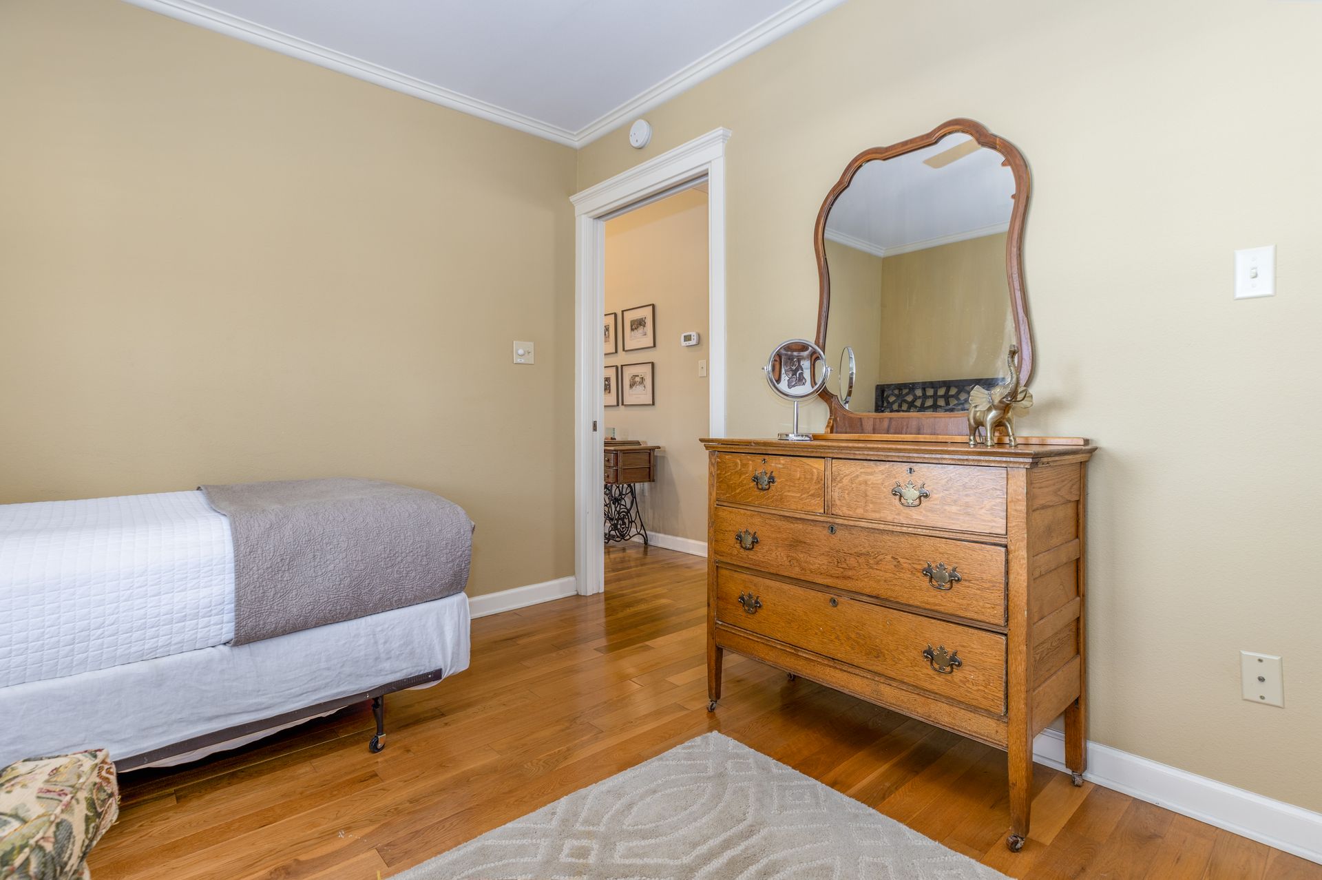 A bedroom with a bed , dresser and mirror.