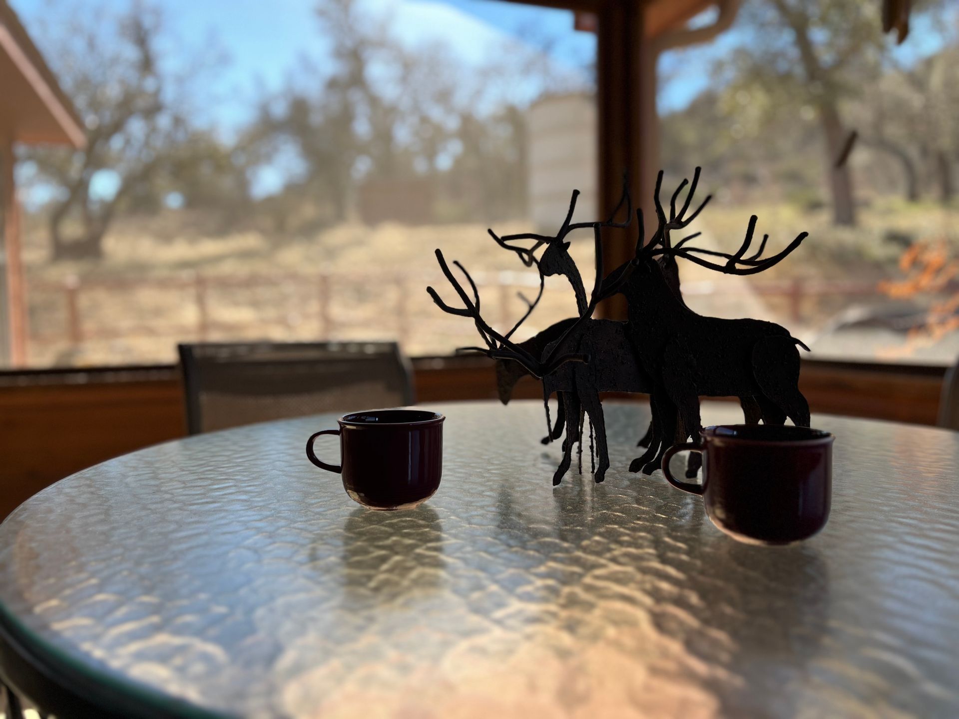 A table with two cups and two deer statues on it