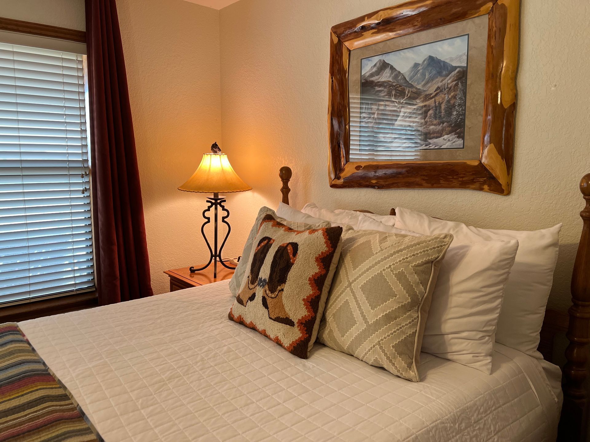 A bedroom with a bed , lamp , and picture on the wall.