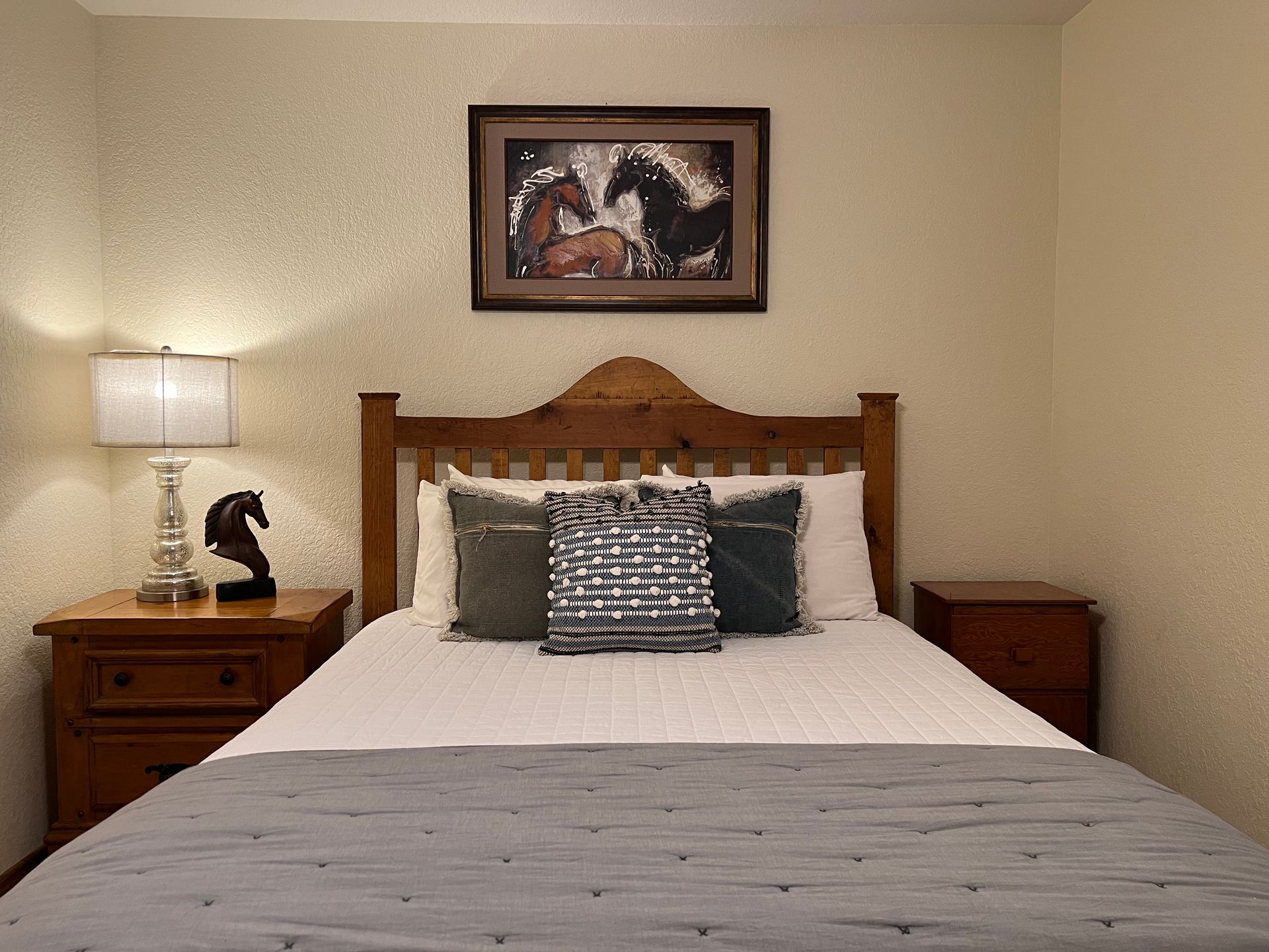 There is a picture of horses on the wall above the bed.