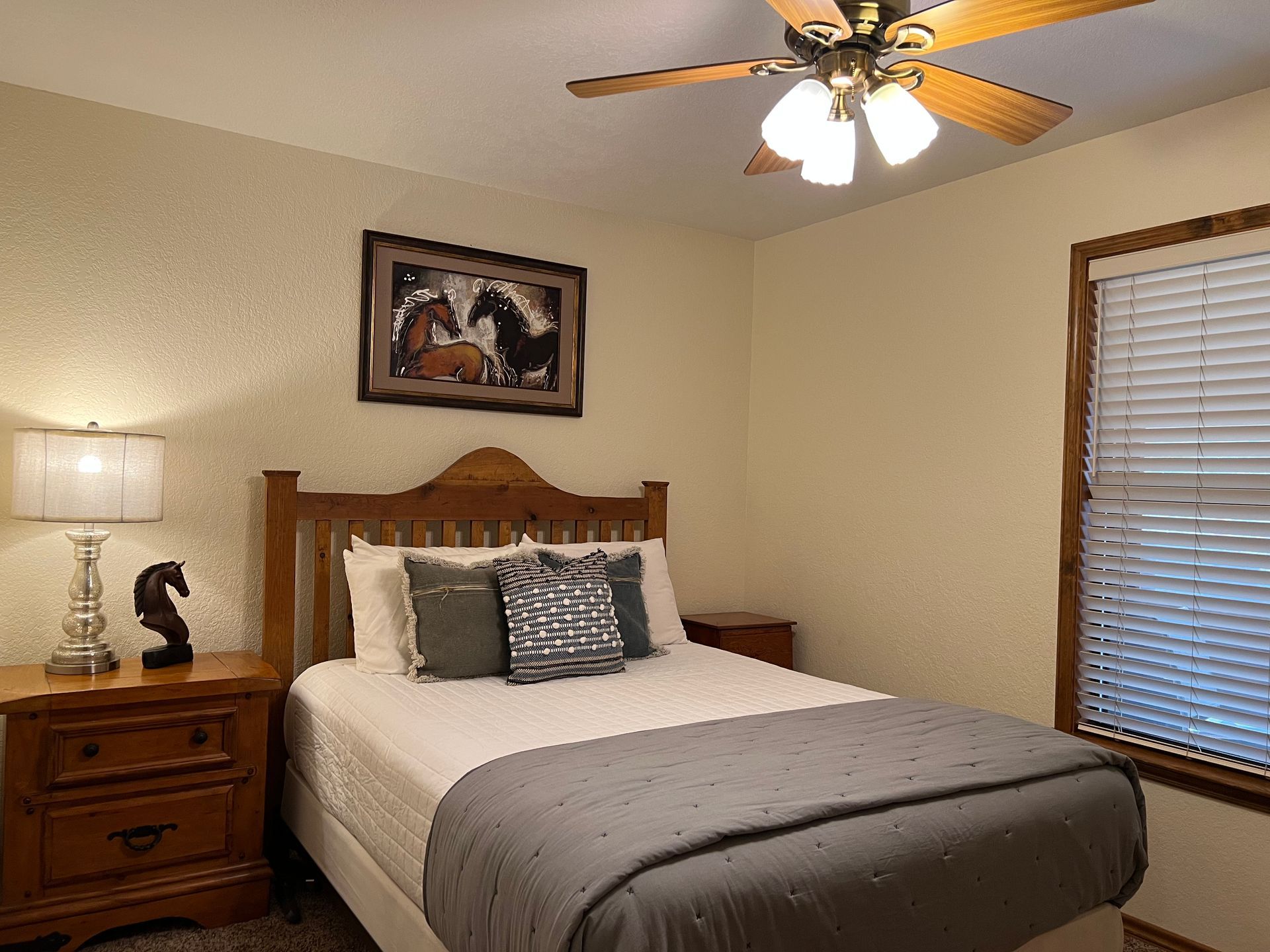 A bedroom with a bed , nightstand , lamp and ceiling fan.