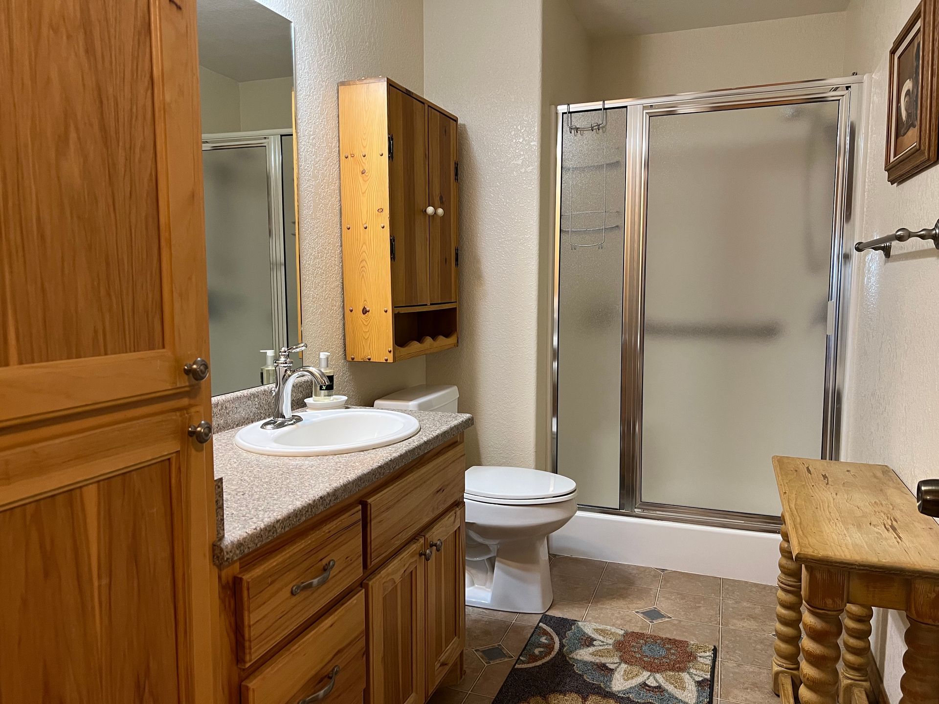 A bathroom with a toilet , sink , mirror and shower.