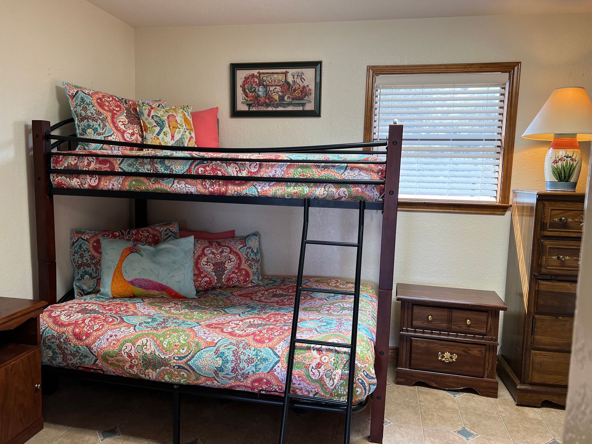 A bunk bed with a ladder in a bedroom next to a window.