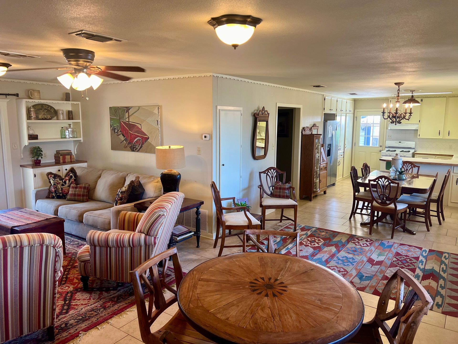 A living room with a couch , chairs , a table and a ceiling fan.