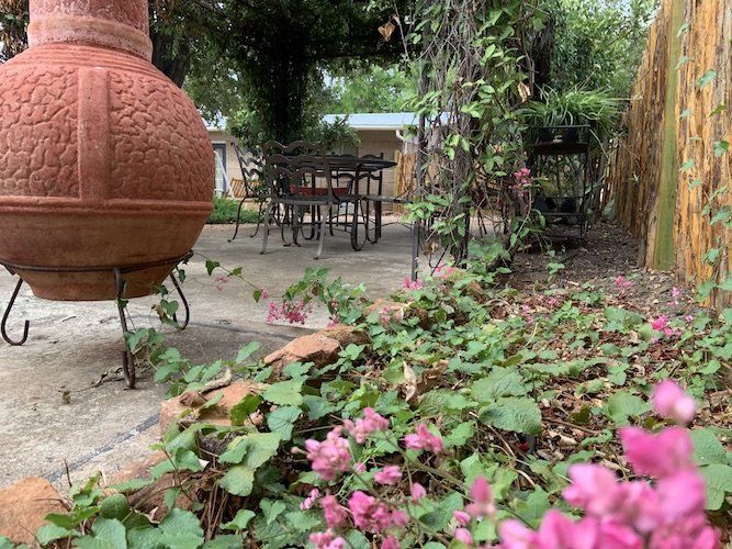 A large vase is sitting in the middle of a garden next to a fire pit.