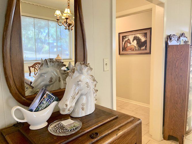 A white horse statue is sitting on a wooden table next to a mirror.