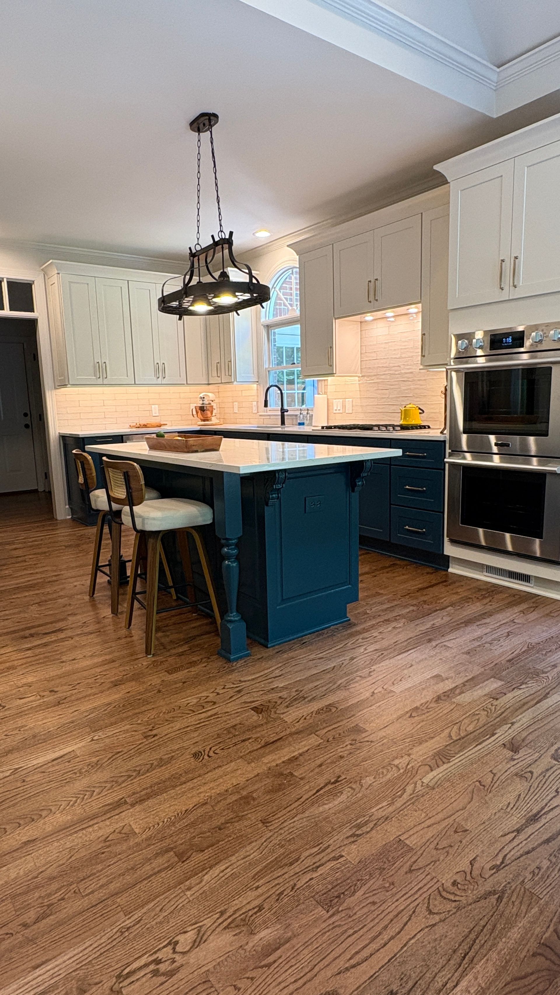 Kitchen with blue island, white cabinets, and wooden floors.