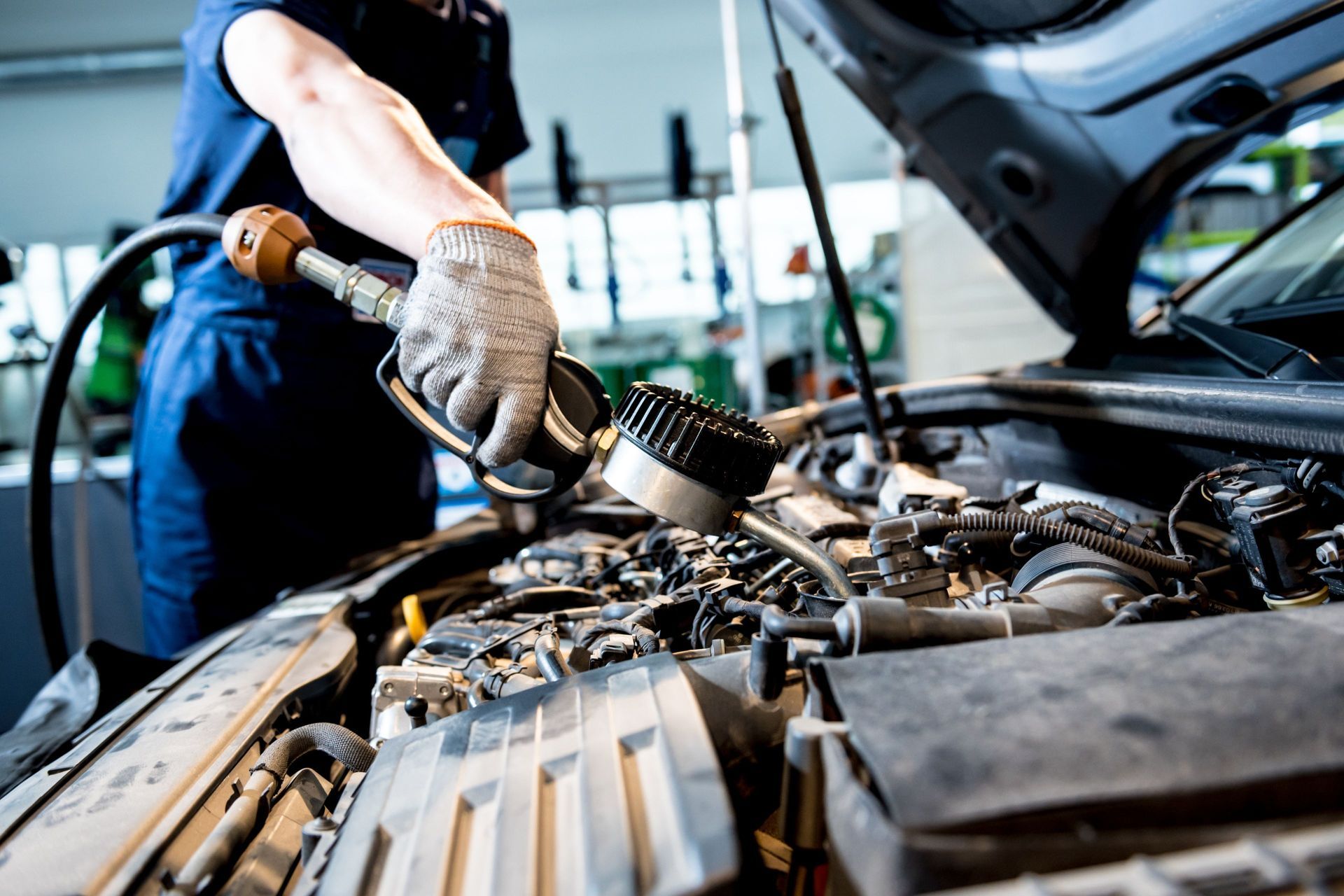 Mechanic checking car engine with a gauge. Mechanic using a diagnostic tool on a car engine in a repair shop.