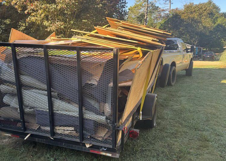 Pickup truck towing a mesh trailer loaded with yellow boards on a grassy roadside