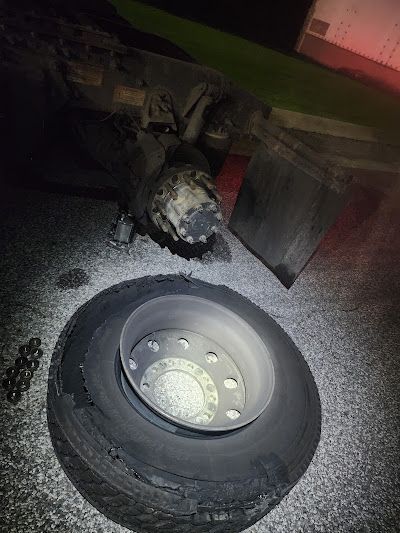 A tire is sitting on the ground next to a truck.