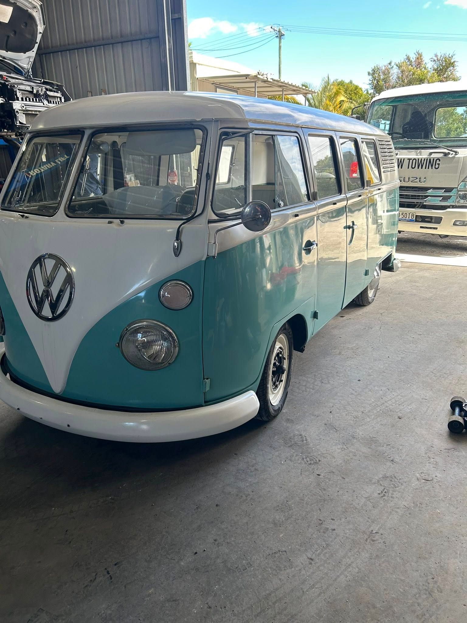 Teal and white Volkswagen bus parked inside a garage.