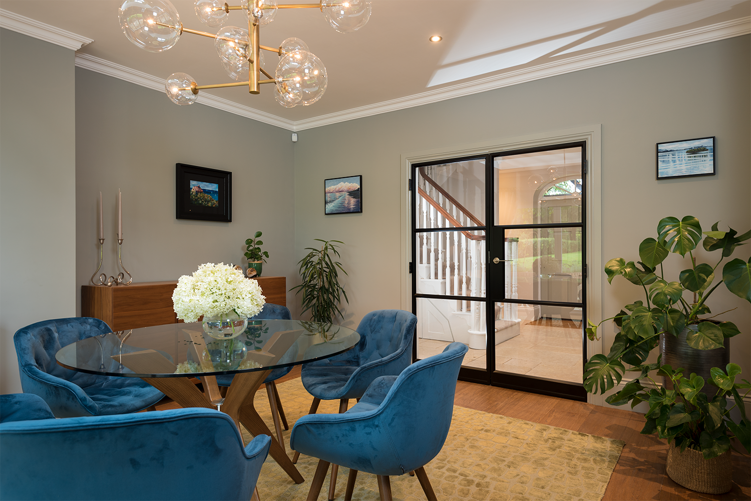 A dining room with a glass table and blue chairs.