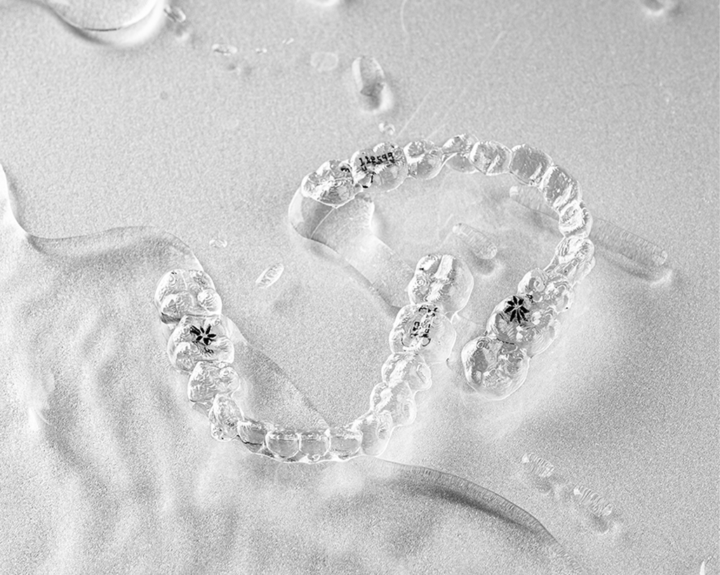 Invisalign clear aligner held next to a patient's smile at Yonsei Baro Orthodontics, Seoul